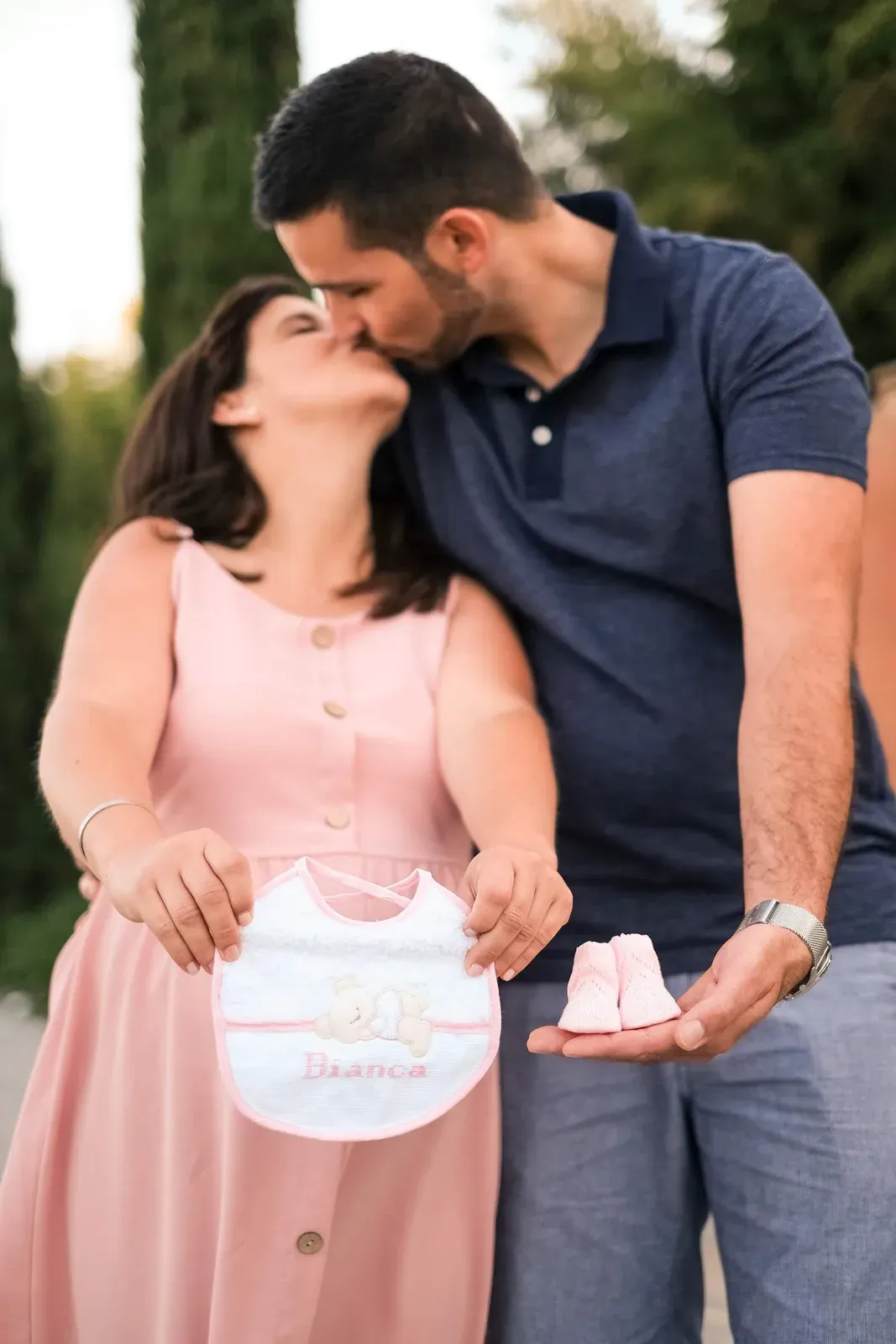 Casal a beijar-se com um babete e sapatinhos de bebé