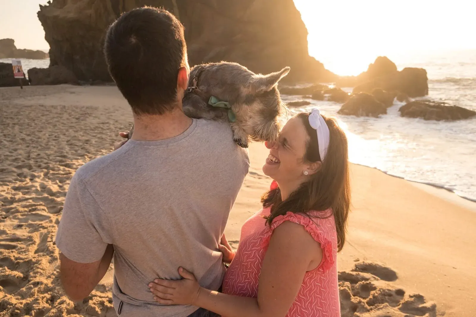 Casal com o cão na praia ao fim da tarde
